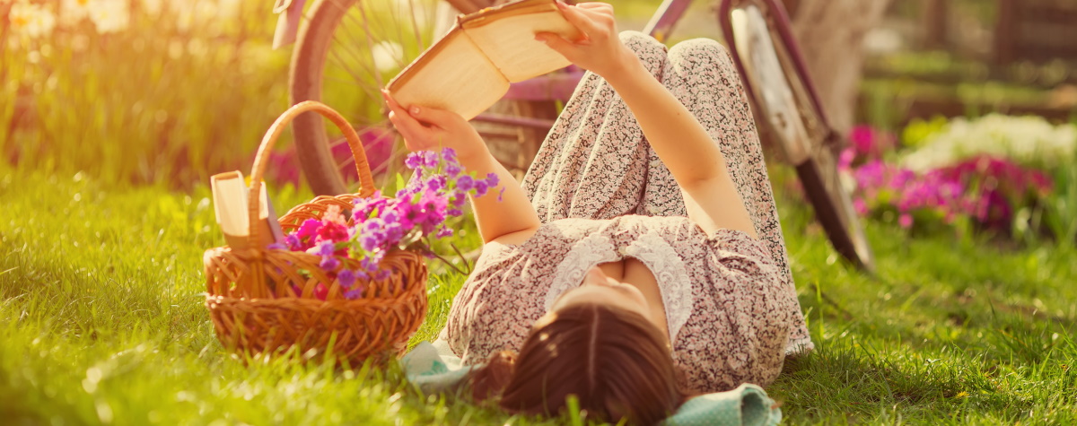 Frau liegt mit Buch in der Sonne - Copyright Kozirsky