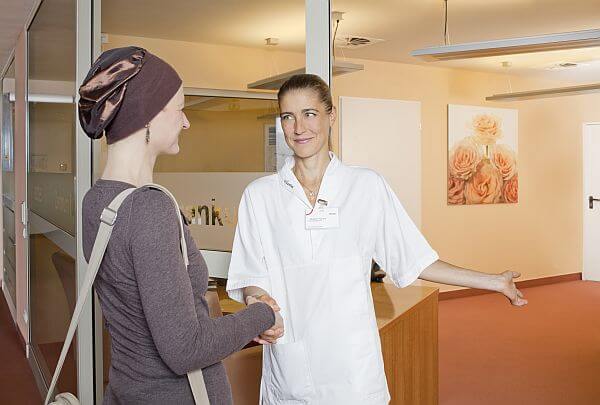 Pflegerin hält Krebs-Patientin die Tür auf