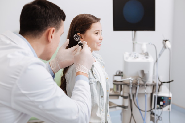 Arzt untersucht die Ohren eines Mädchens mit einem medizinischen Gerät