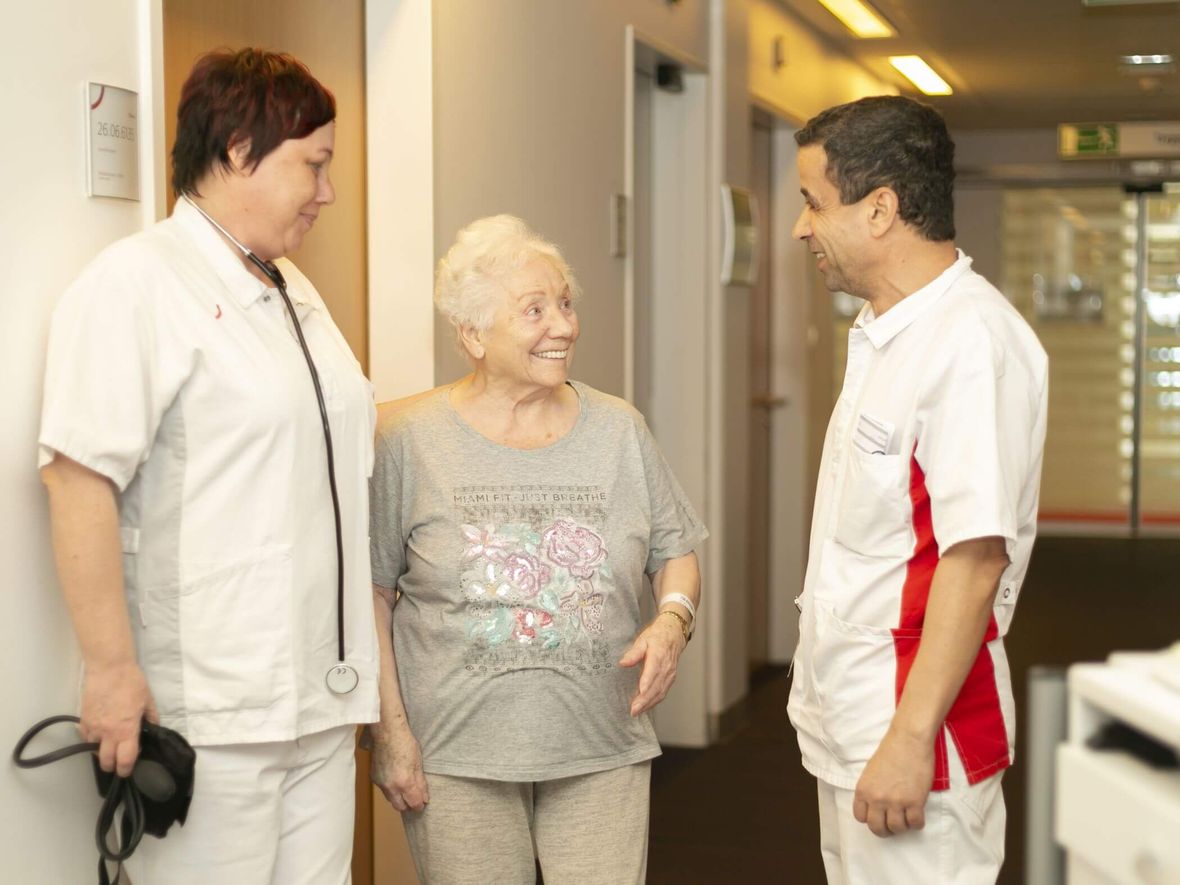 Patientin und Pfleger der Orthopädie im Gespräch auf den Klinikflur