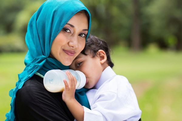 junge Muslima mit Kleinkind auf dem Arm