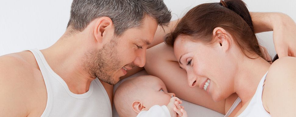 Vater und Mutter liegen mit einem Baby in der Mitte auf weißem Hintergrund