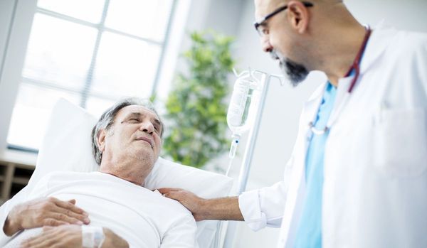 Arzt spricht mit liegendem Patient mit Prostatakrebs