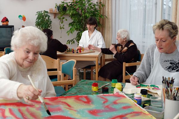 Pflegefachkraft spielt mit gerontopsychiatrischen Patienten Gesellschaftsspiele