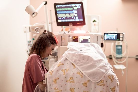 Pflege im Krankenhaus Neukölln: Das Bild zeigt eine Pflegerin am mit Tüchern bedeckten Inkubator.