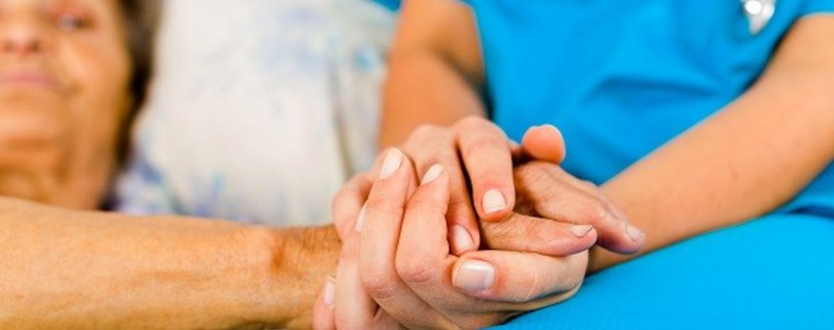 Eine Pflegende hält die Hand einer Patientin.
