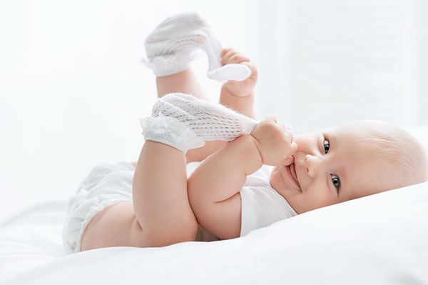 Ein fröhliches kleines Baby auf einem Bett und weißem Hintergrund