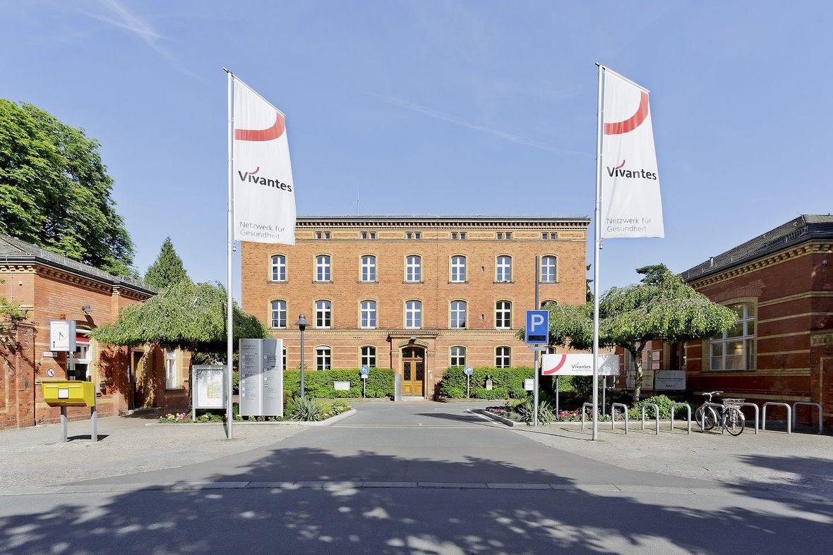 Pflege im Wenckebach-Klinikum in Berlin-Tempelhof: Das Bild zeigt den Eingangsbereich des Krankenhausgeländes mit drei Backsteinbauten, eins davon im Hintergrund sowie links und rechts je ein Quergebäude.
