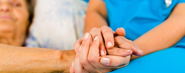 Eine Pflegende hält die Hand einer Patientin.