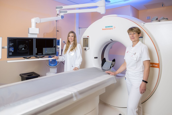 zwei Kolleginnen stehen vor dem CT-Gerät im Röntgenraum